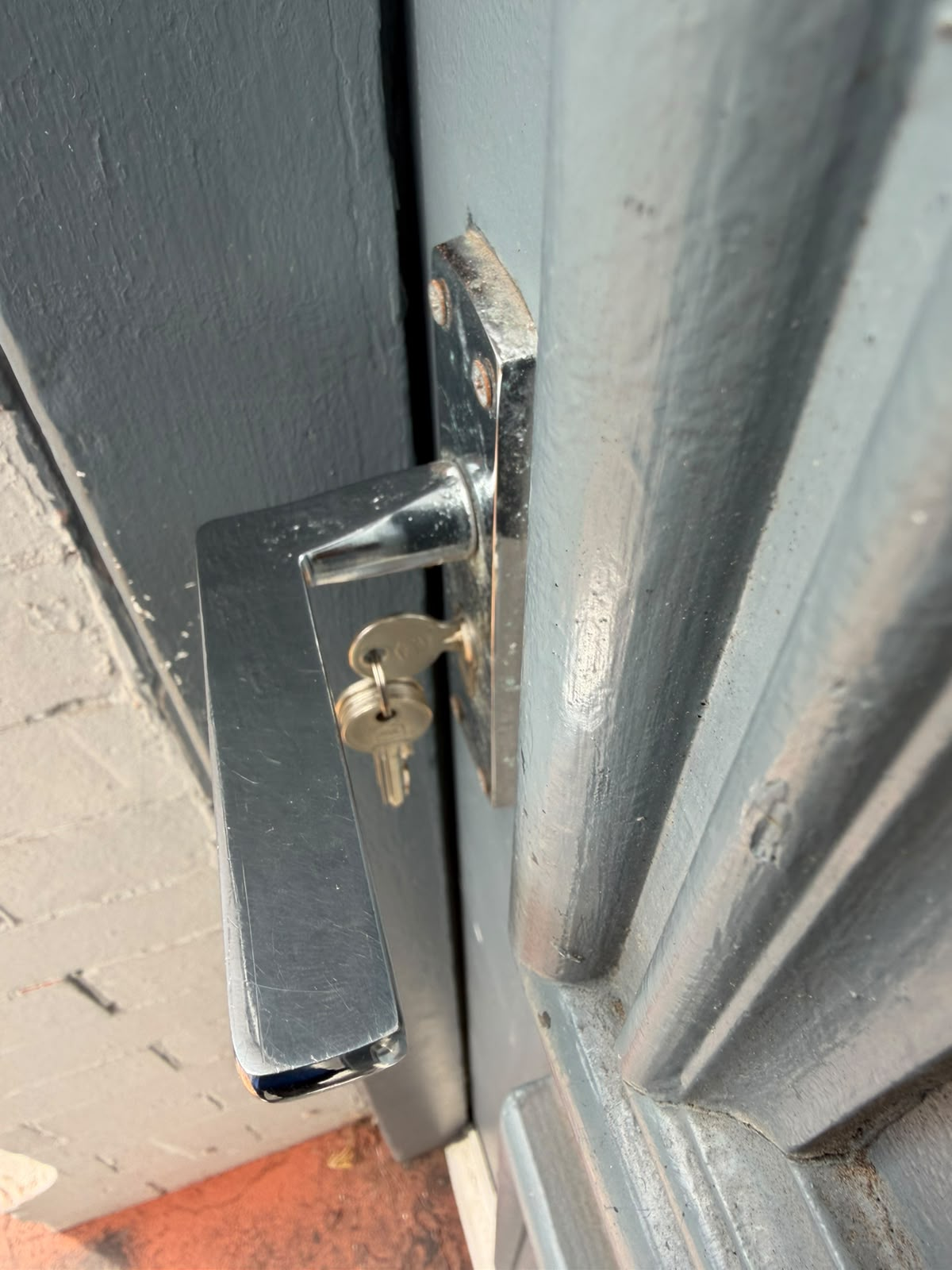 Chrome lever handle with new key inserted on a grey painted front door after cylinder replacement by A Slater & Son
